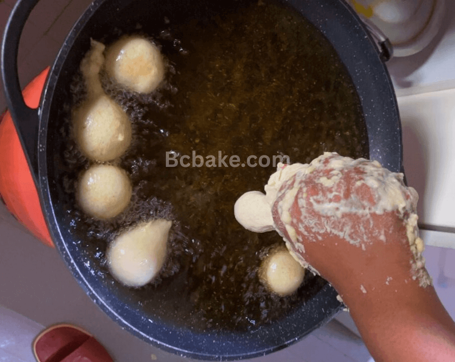 Adding the Nigerian puff puff dough to the hot oil on fire